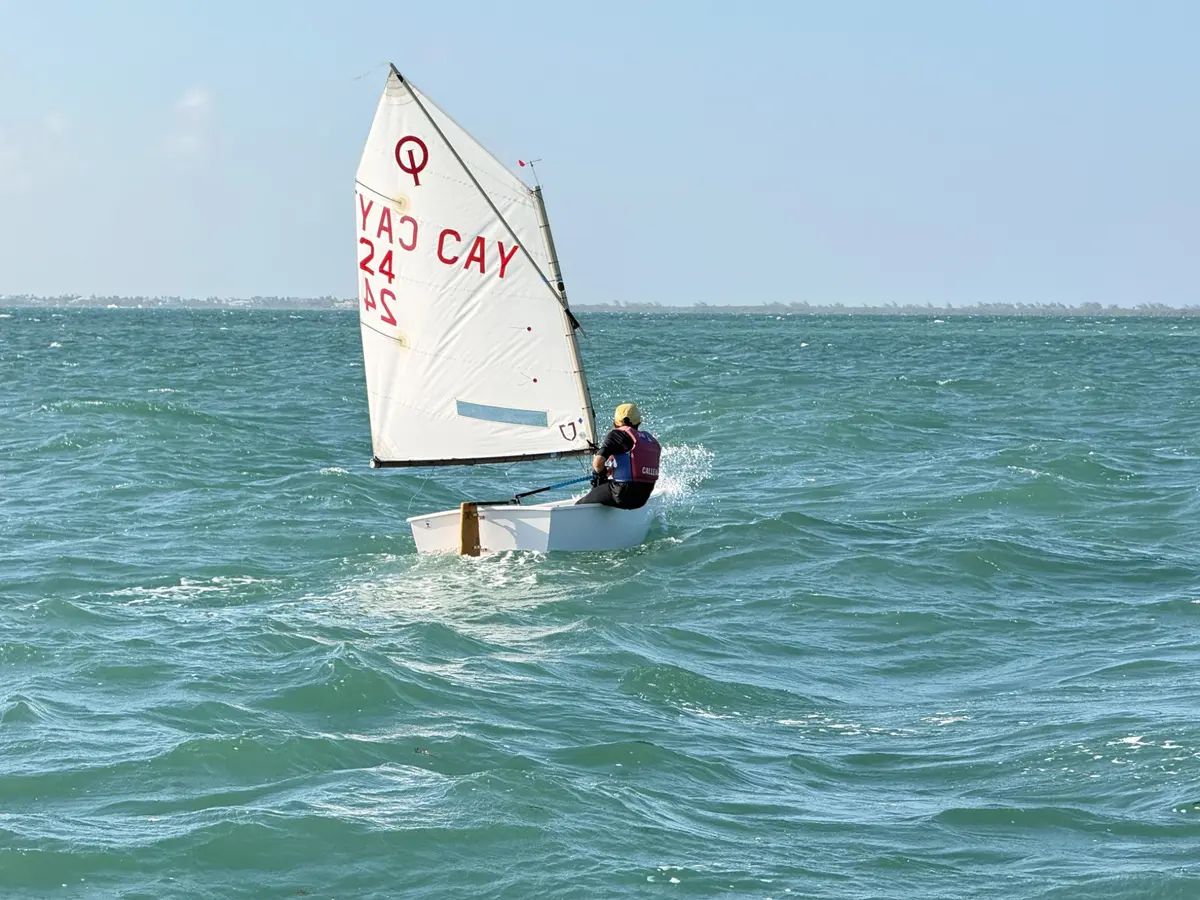 A child sailing an Optimist on the North Sound